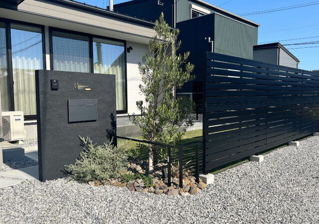 ブラック門柱とタイルデッキ、目隠しのある平屋外構