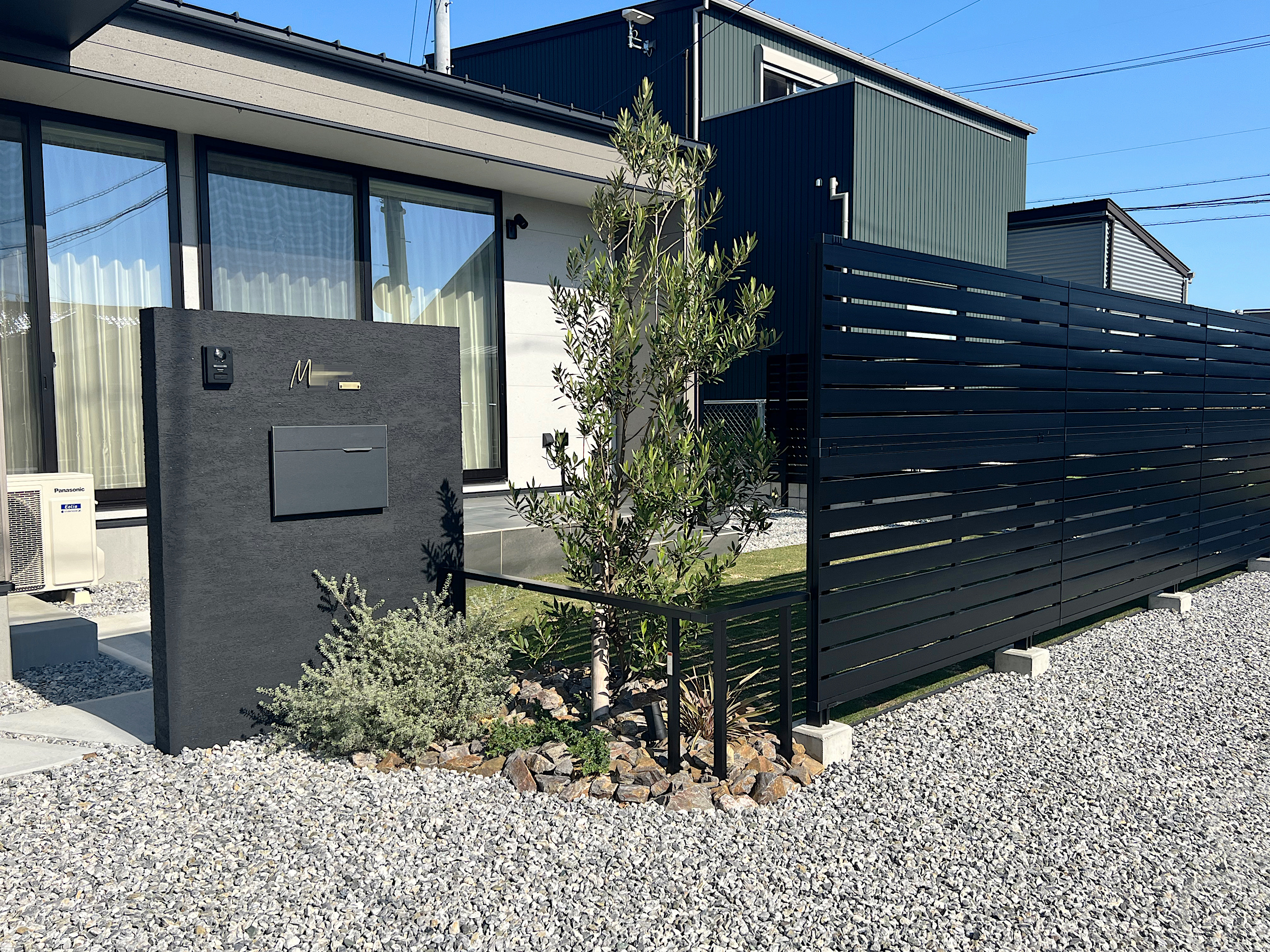 ブラック門柱とタイルデッキ、目隠しのある平屋外構